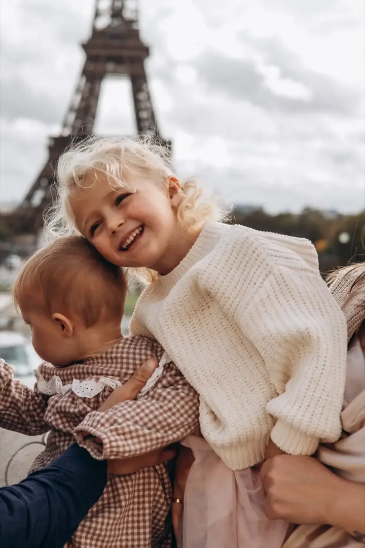 Sister kissing baby brother Eiffel Tower Paris
