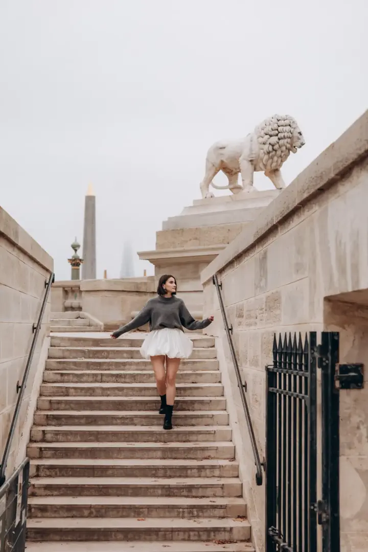 Woman descending stairs lion statue Paris cinematic